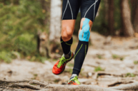 Person in athletic wear with phone armband running on a rocky path in the woods.”